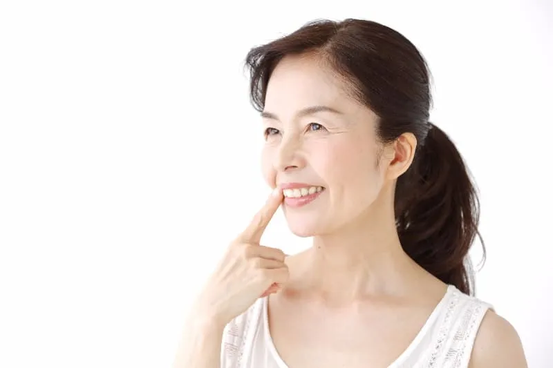 口を指さしている女性